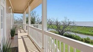 A covered porch with a view of a river and trees. - Magnolia Cottage R7 (Lafitte)