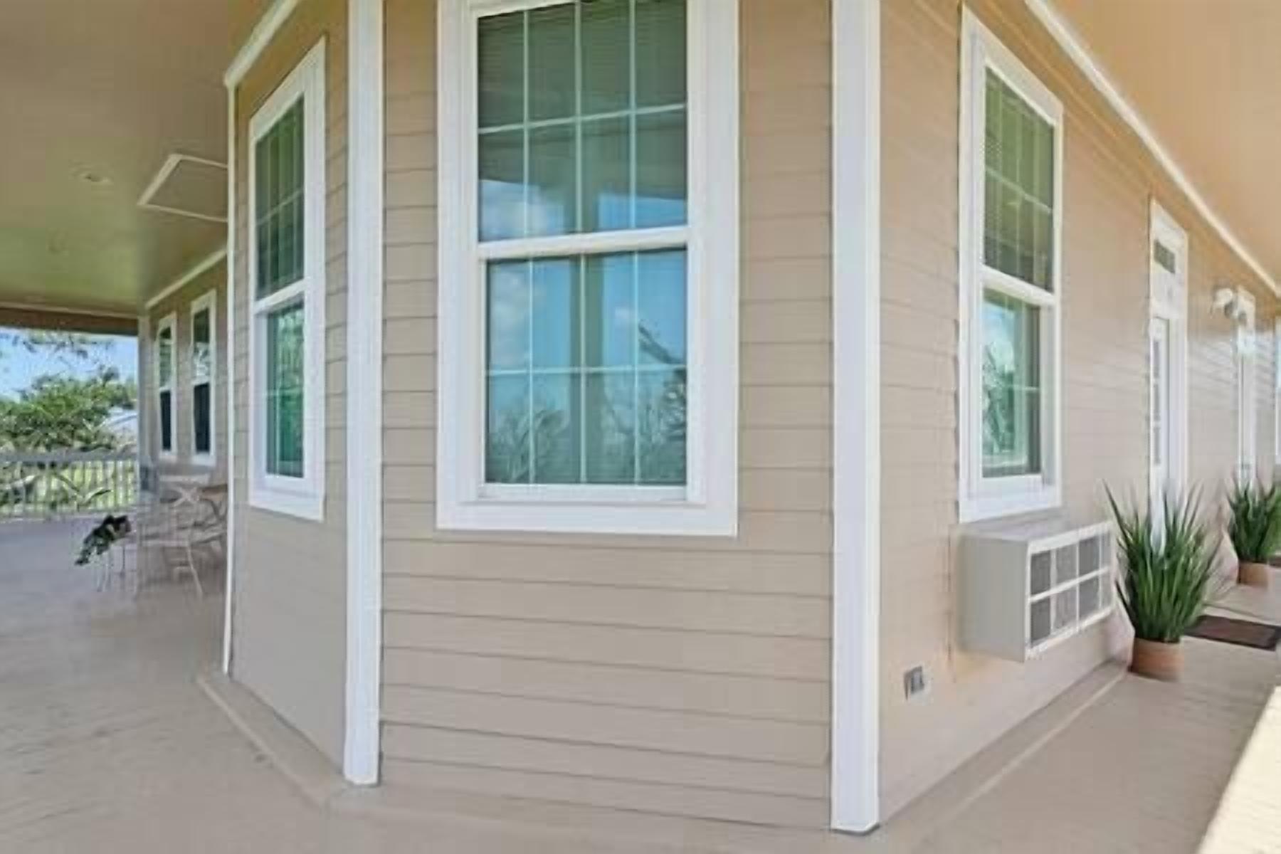 A covered porch with large windows and a beige exterior wall.