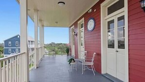 A covered porch with a red exterior, white doors, and a clock on the wall. - Oak Cottage R304 (Lafitte)