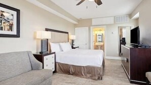 A hotel room with a bed, a desk, a television, and a ceiling fan. - Cypress Cottage R4 (Lafitte)