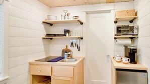 Una cocina compacta con armarios de madera, un lavamanos integrado y una cafetera.