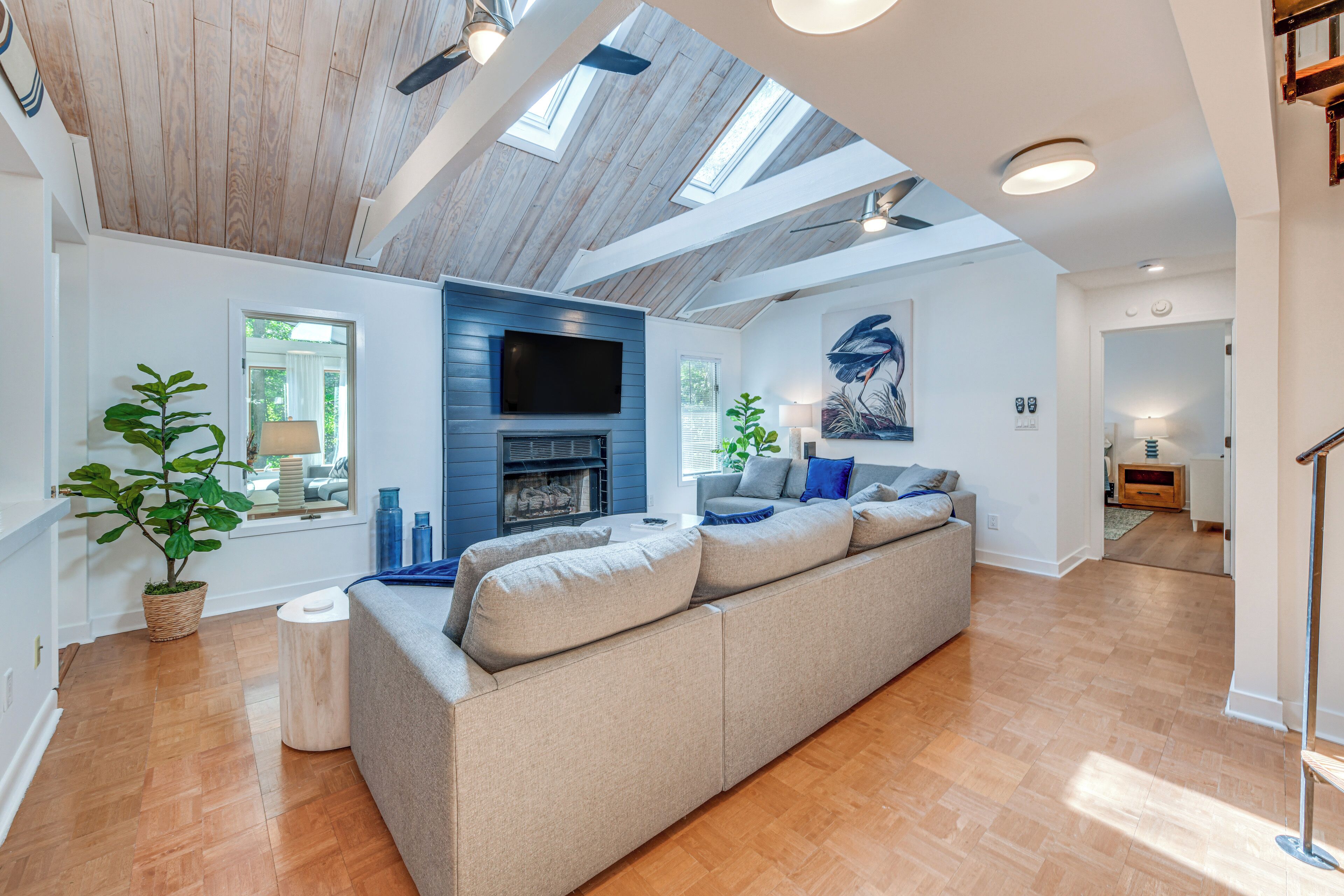 A spacious living room with a large sofa, a fireplace, and a skylight.