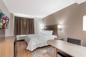 Habitación de hotel con cama, mesitas de noche, televisor, escritorio y una silla.
