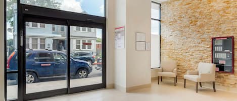 A reception area with a stone wall, two chairs, and a fire alarm center.