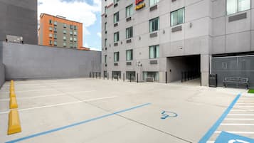 A parking area with marked spaces, a wheelchair-accessible spot, and a building with a sign reading 'Red Roof Plus'.