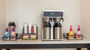 Eine Kaffeestation mit zwei Kaffeemaschinen, Einwegbechern und verschiedenen Zusätzen.
