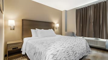 Una habitación de hotel con una cama grande, lámparas de noche, una mesita de noche, una ventana con cortinas y un calefactor de pared.