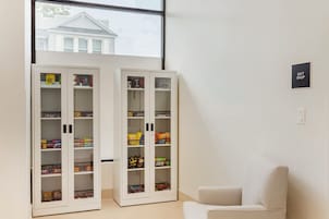 Una habitación con dos armarios blancos que contienen aperitivos y una pequeña silla blanca.