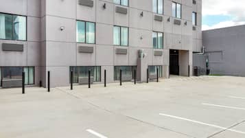 A modern building with a flat facade, multiple windows, and a parking area with marked spaces.