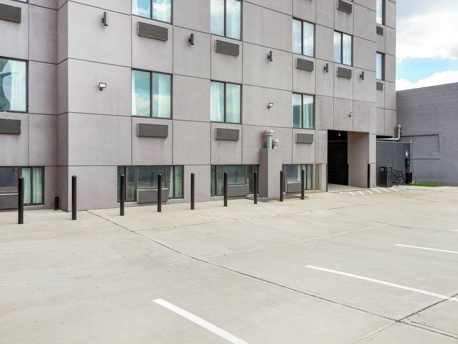 A modern building with a flat facade, multiple windows, and a parking area with marked spaces.