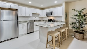 A modern kitchen with white cabinets, stainless steel appliances, a marble countertop, and a potted plant. - Turtle Cove at Siesta Dreams - private 2BR, 1BA apartment near Fort Myers Beach! (Fort Myers Beach)