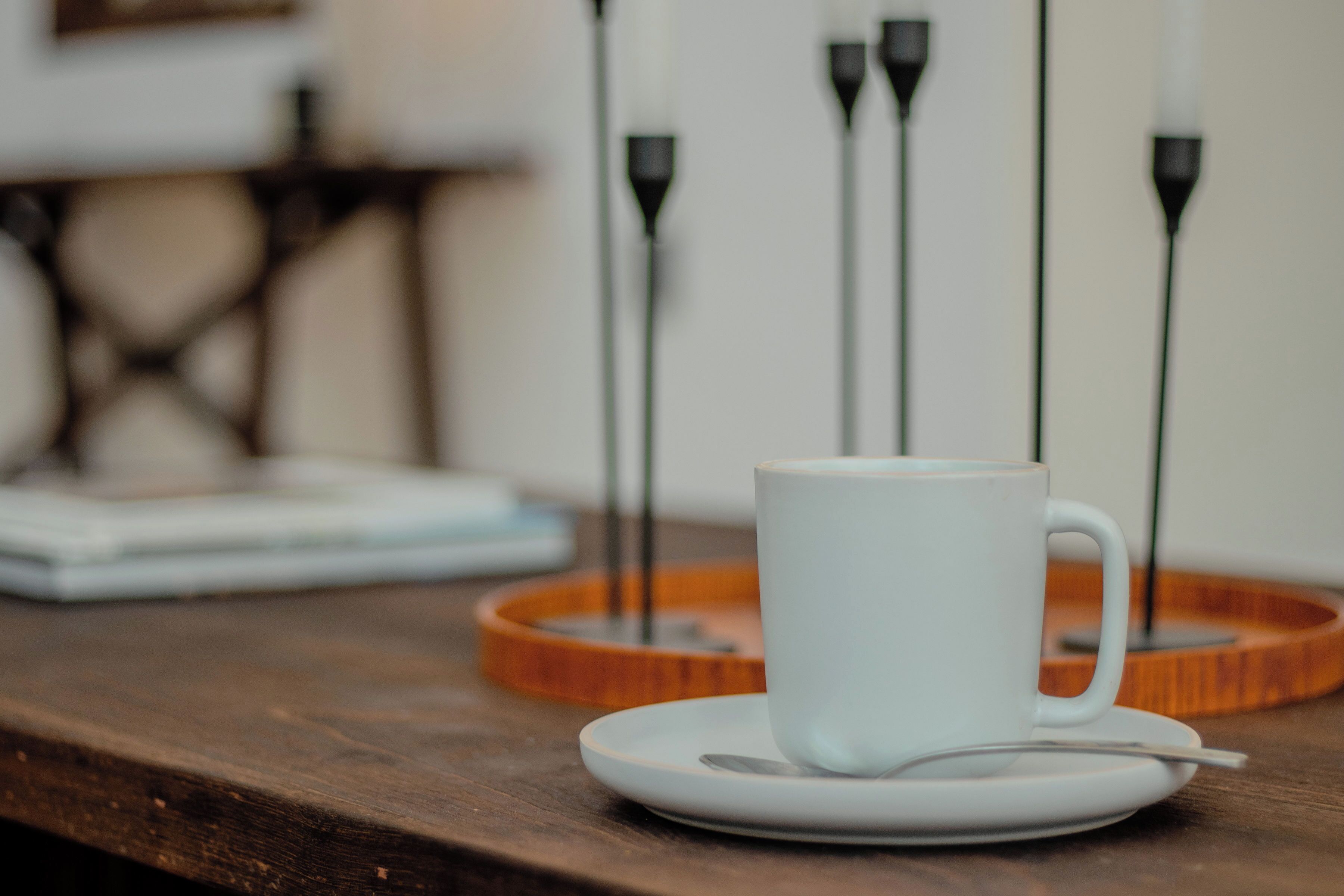 A white cup on a saucer with a spoon on a wooden tray.