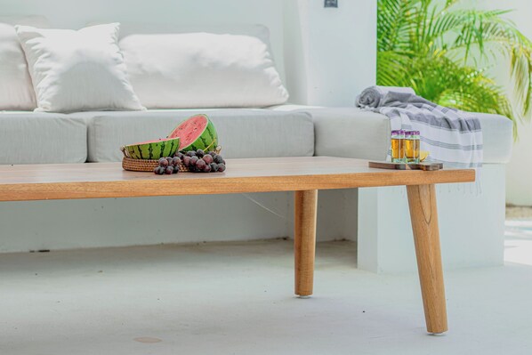 A wooden table with a watermelon, grapes, and a glass of amber liquid.