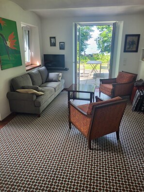 Una sala de estar con un sofá, sillones, una mesa de centro, un televisor de pantalla plana y un piso con diseño.