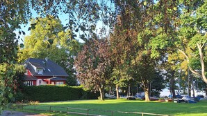 A park with a red house, green grass, and trees.