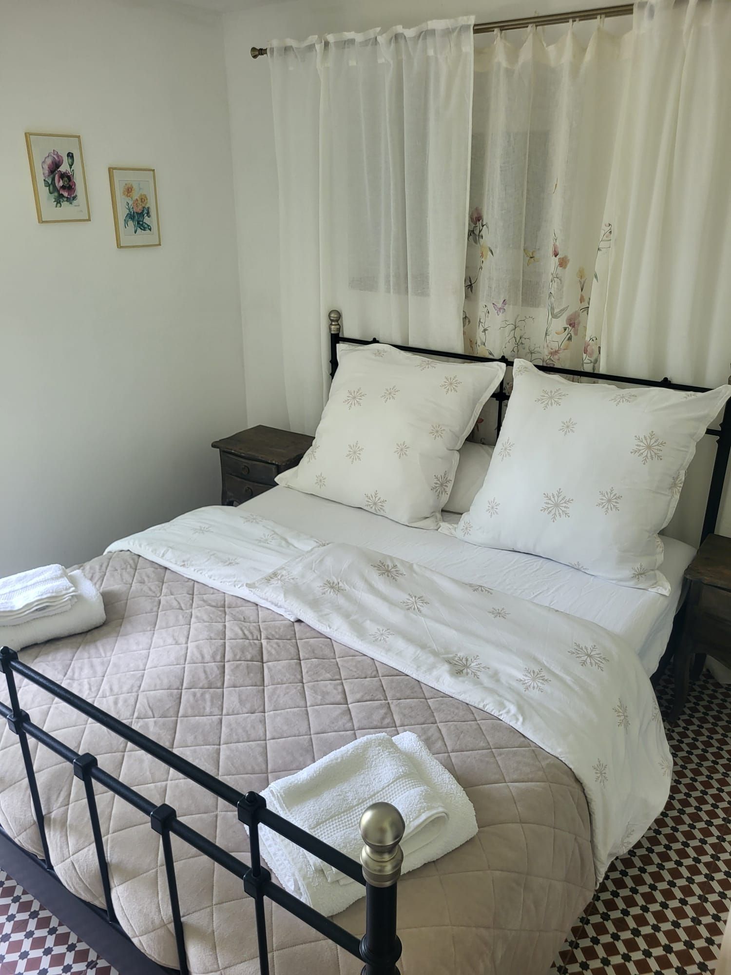 Un lit avec une couvre-lit matelassé et des oreillers, une table de chevet et une petite table d’appoint.