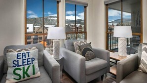 A modern living room with grey sofas, two lamps, and a view of snow-covered mountains through large windows. - Ski-in, Ski-out 1 Bedroom at Peak 9 Near Main Street (Breckenridge)