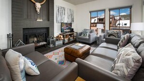 A modern living room with a fireplace, comfortable seating, and large windows offering a view of the outdoors. - Ski-in, Ski-out 1 Bedroom at Peak 9 Near Main Street (Breckenridge)
