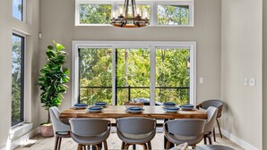 Un coin repas avec une table en bois, six chaises et un lustre.
