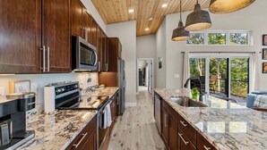 Une cuisine moderne avec des meubles en bois foncé, des appareils électroménagers en acier inoxydable et un grand îlot central doté d’un évier.