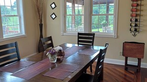 Une salle à manger avec une table en bois, des chaises, un lustre et un meuble à vin.