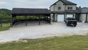 Une maison dotée d’un patio couvert, d’un garage et d’une allée gravillonnée.