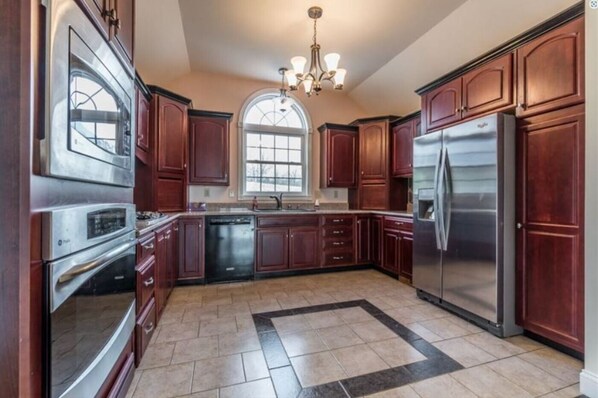 A spacious kitchen with dark wood cabinets, stainless steel appliances, and a large window. - View on the Ridge close to Ark Encounter. (Williamstown)