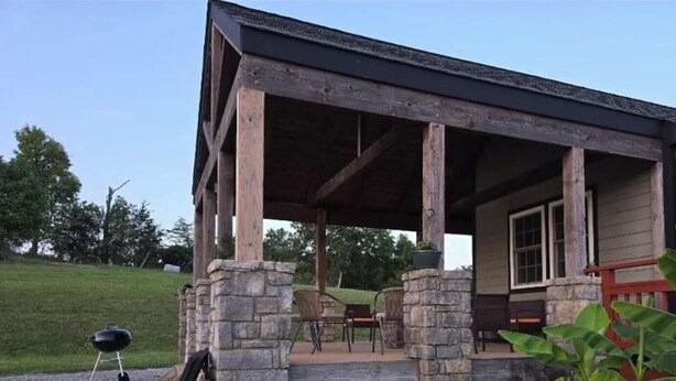 Un espace extérieur abrité, doté de piliers en pierre, d’un barbecue et de mobilier d’extérieur.
