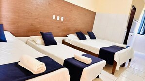 A hotel room with three single beds, each with a white mattress and dark blue headboard. - INFINITY POUSADA (Aracaju)