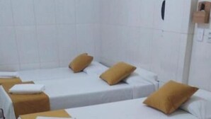 A row of single beds with white linens and brown headboards in a clean, tiled room. - INFINITY POUSADA (Aracaju)