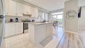 A modern kitchen with white cabinets, a central island, and a dining area with a view.
