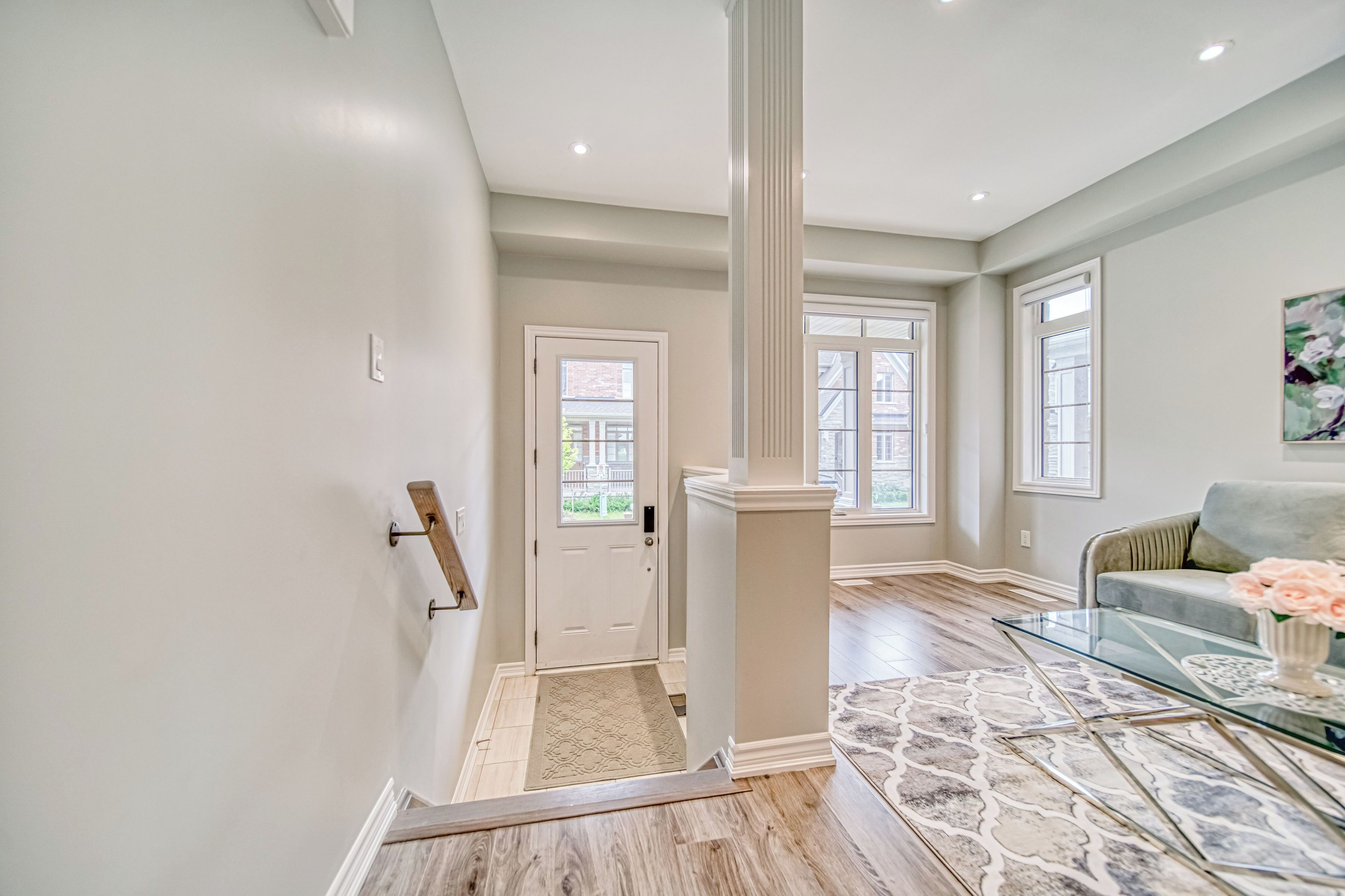 A spacious living area with a glass coffee table, a sofa, and a door leading to another room.