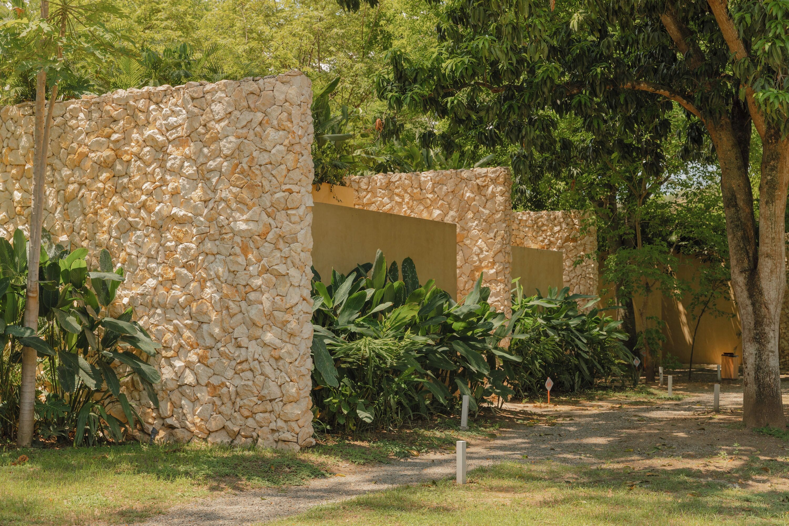 A pathway leading to stone structures surrounded by lush greenery.