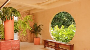 Una habitación con un ventanal circular, un banco de madera y plantas en macetas.