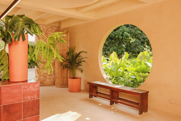 Una habitación con un ventanal circular, un banco de madera y plantas en macetas.
