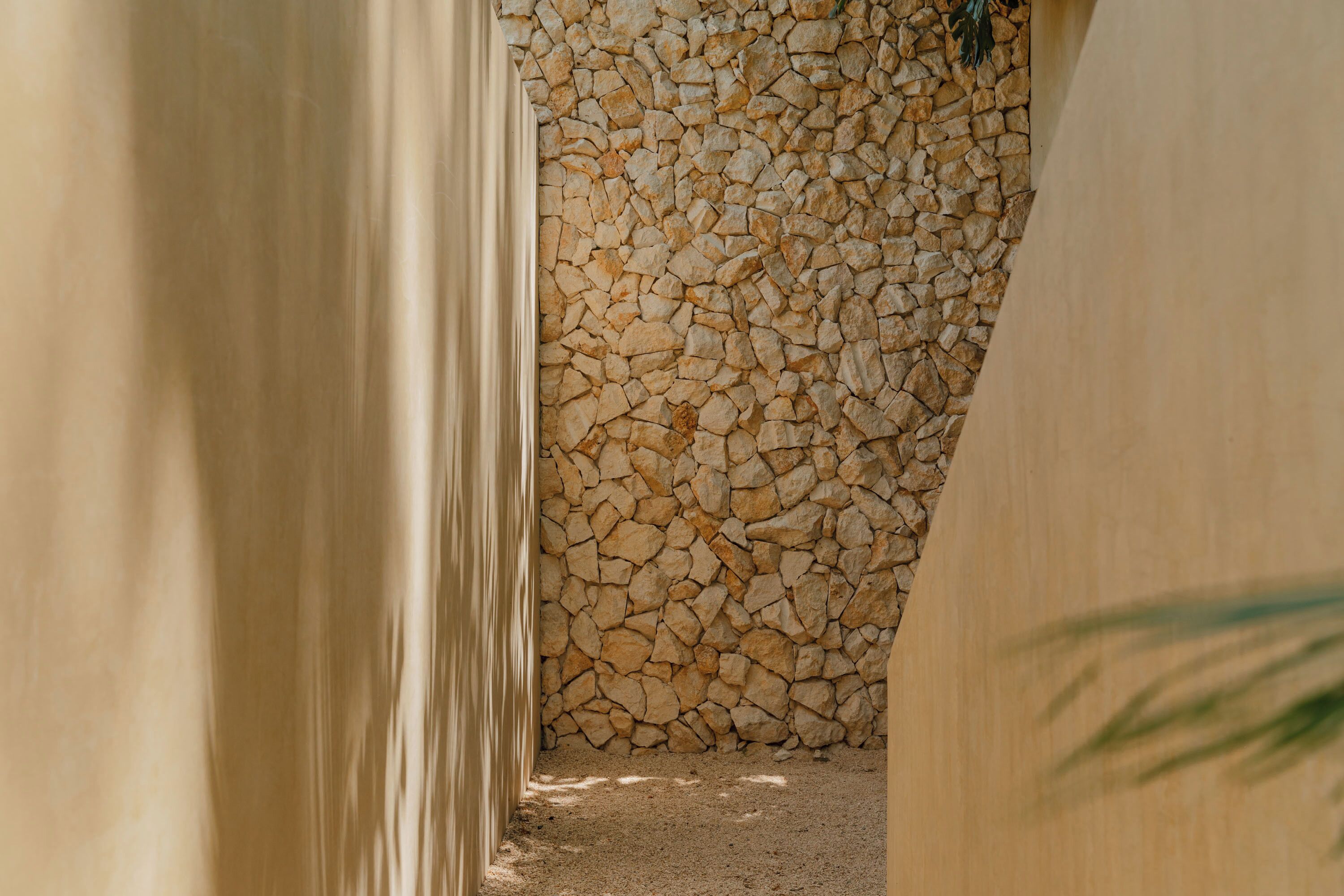 A corridor with a stone wall on one side and a plain wall on the other.