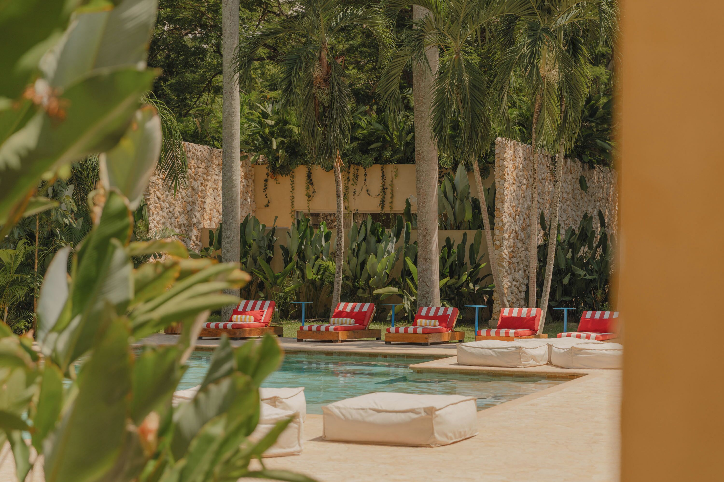 Un área junto a la piscina con sillones de descanso y una pared de piedra.