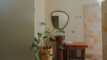 A bathroom with a wooden vanity, a mirror, a sink with a stone basin, and a potted plant.