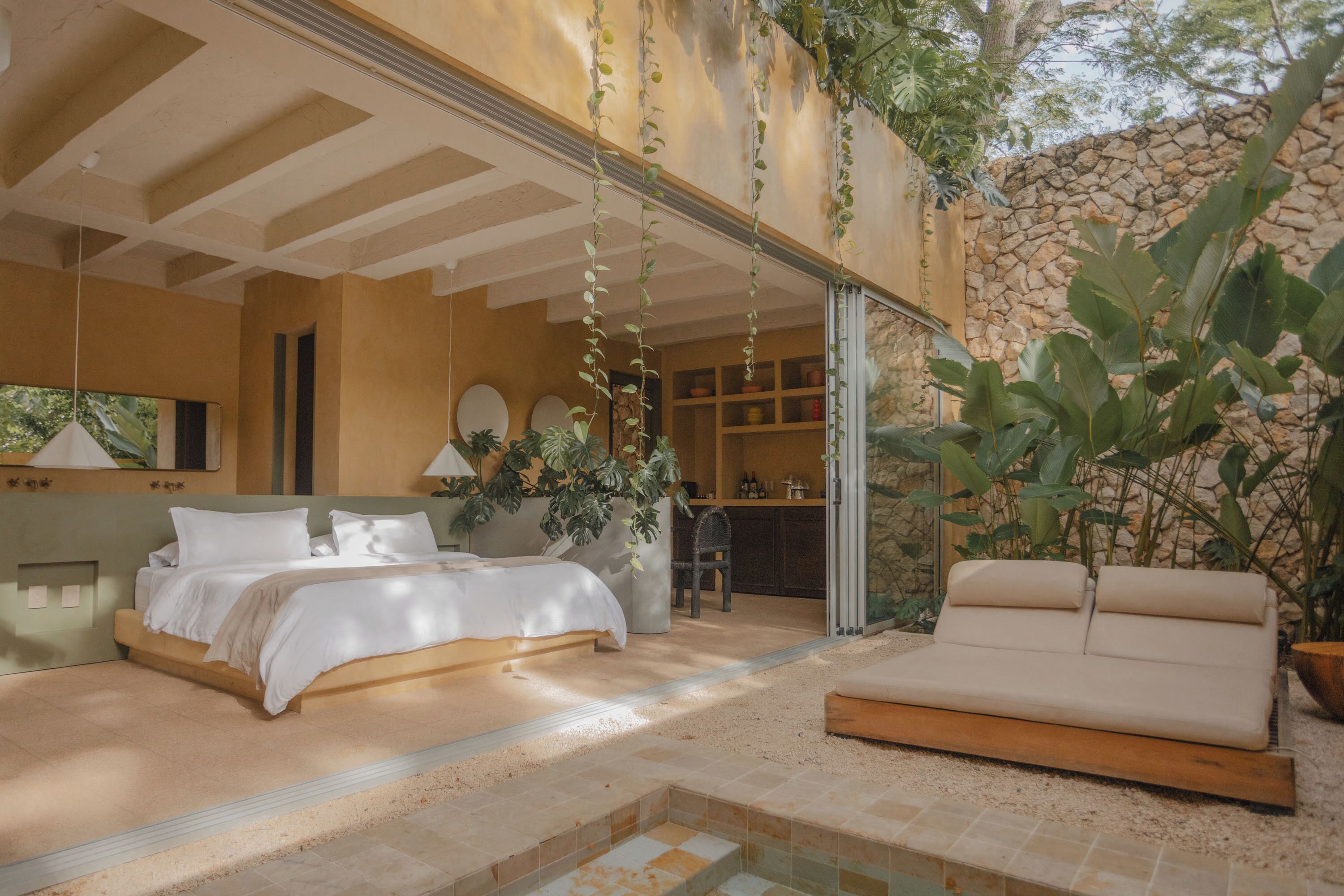 Quarto com cama, sofá e pequena área de piscina.