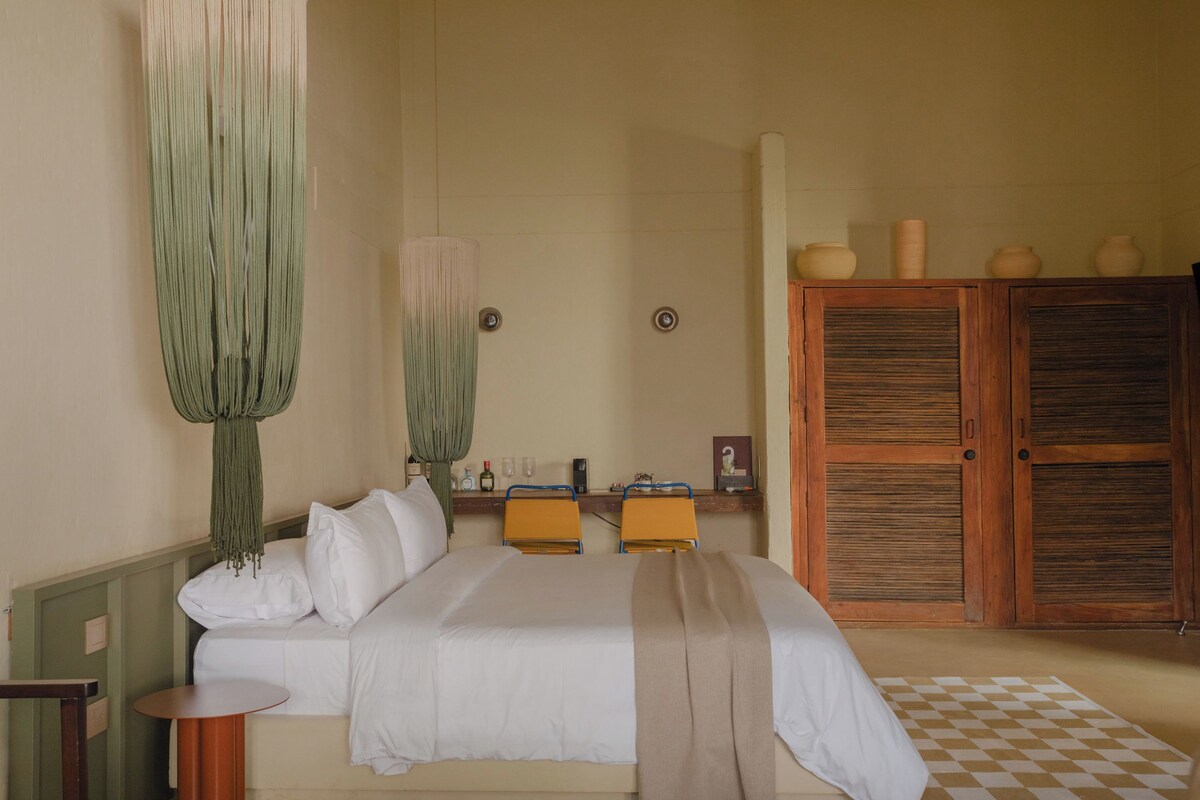 A bedroom with a bed, bedside tables, a wooden wardrobe, and a checkered floor.