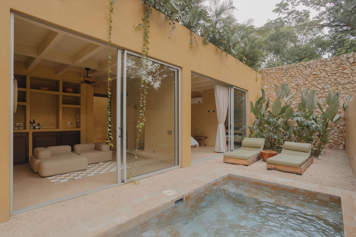A modern outdoor living area with a pool, seating, and a stone wall.