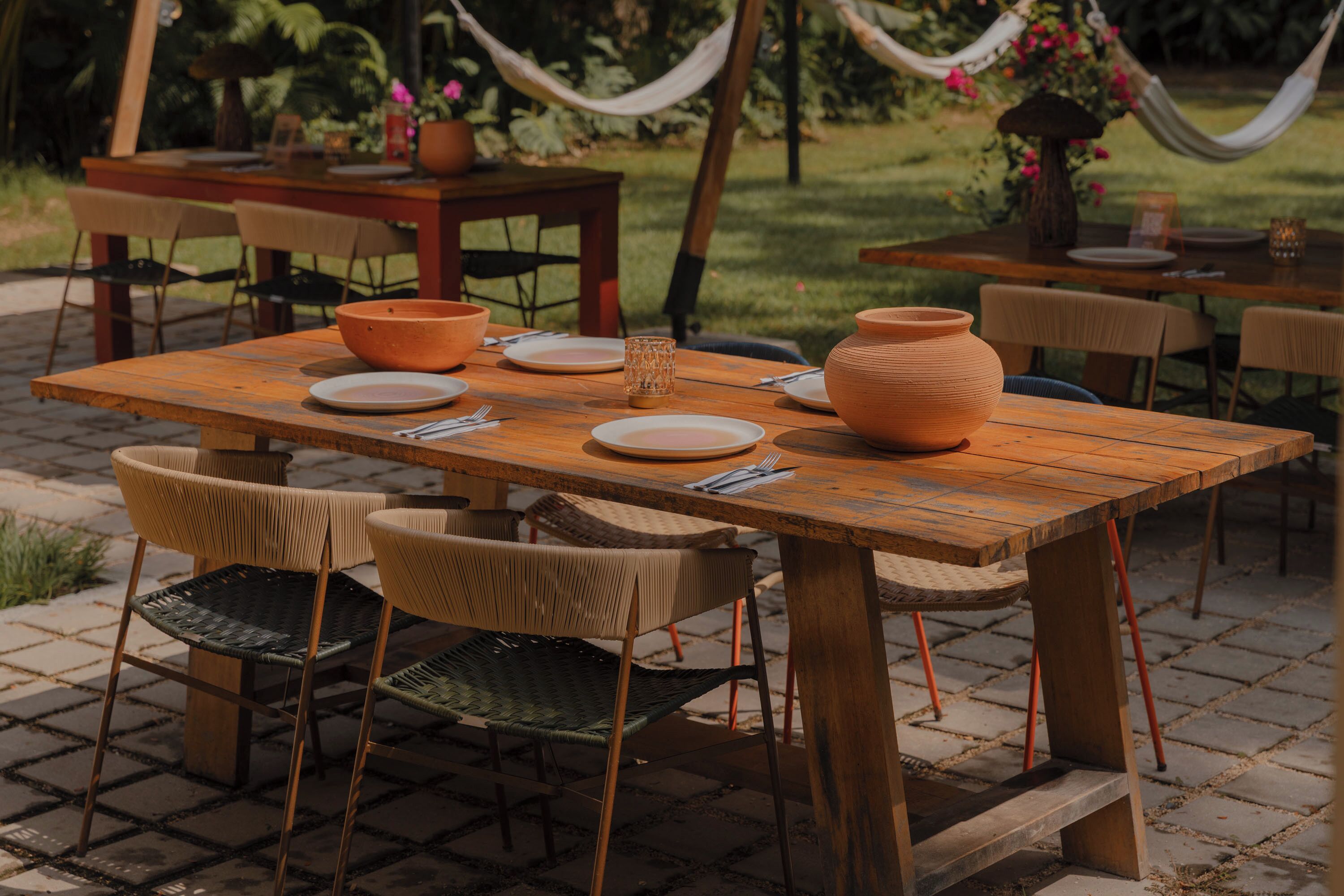 An outdoor dining area with a wooden table, chairs, and a rustic setting.