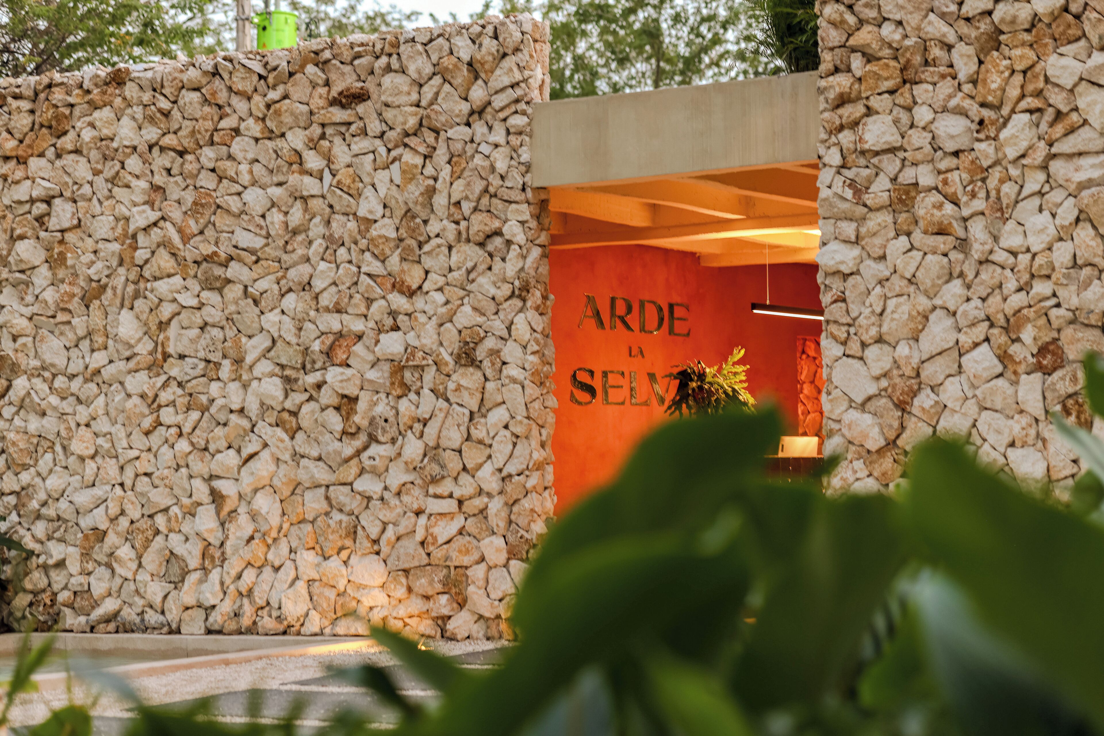 Um muro de pedra com uma placa que diz 'ARDE LA SELVA'.
