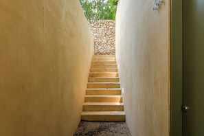 Una escalera estrecha con un muro de piedra en la parte superior, que conduce a una puerta.