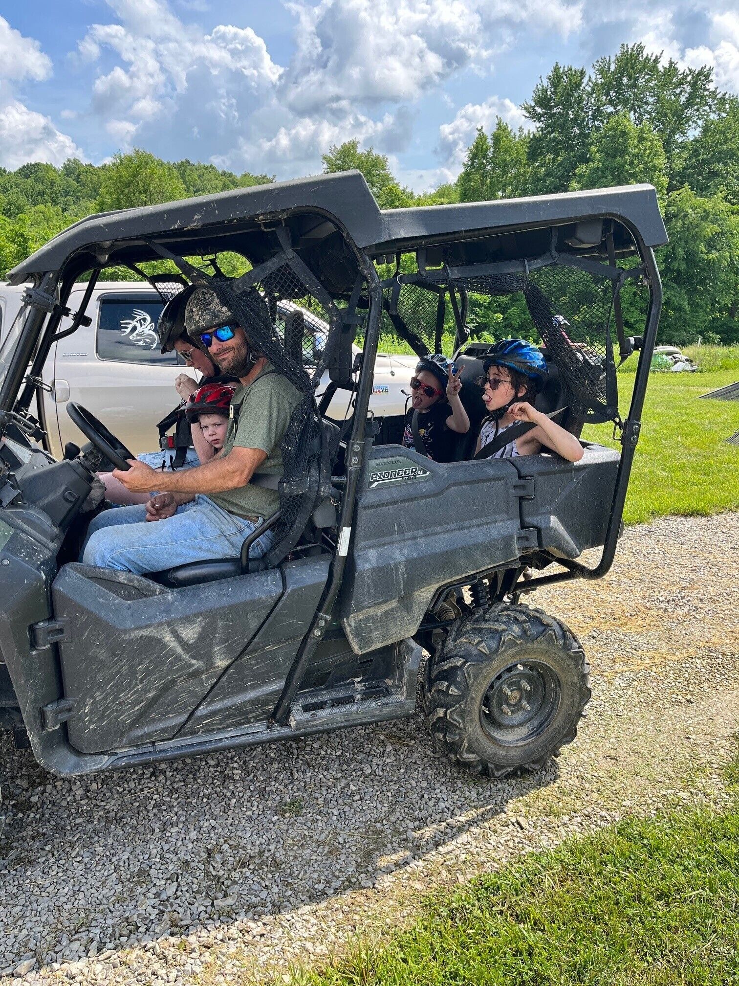 Une famille se promène dans un véhicule de type voiturette de golf au design robuste, équipé de dispositifs de sécurité tels que des casques et des gilets de sauvetage.