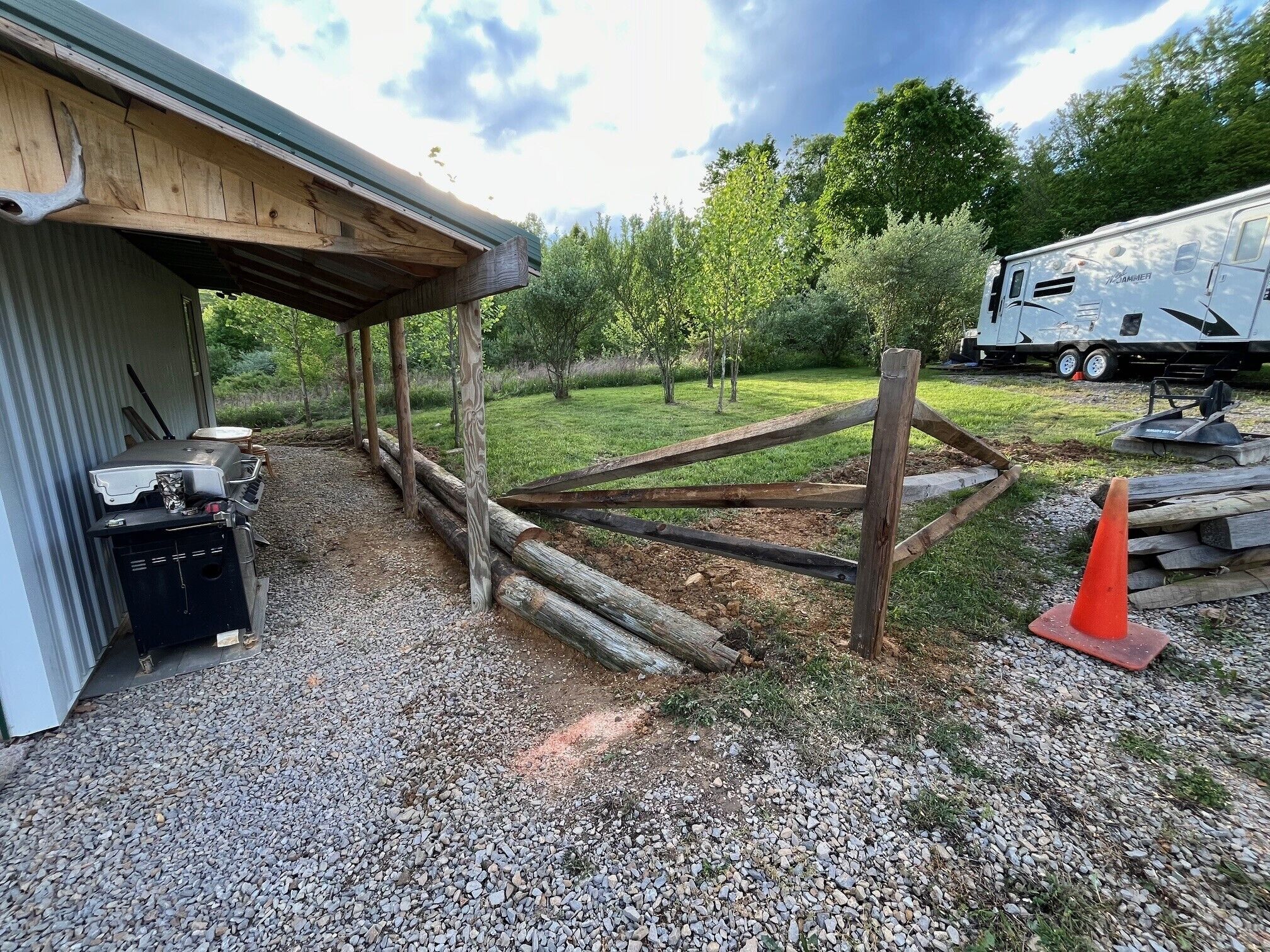 A gravel driveway leading to a wooden structure with a covered porch.