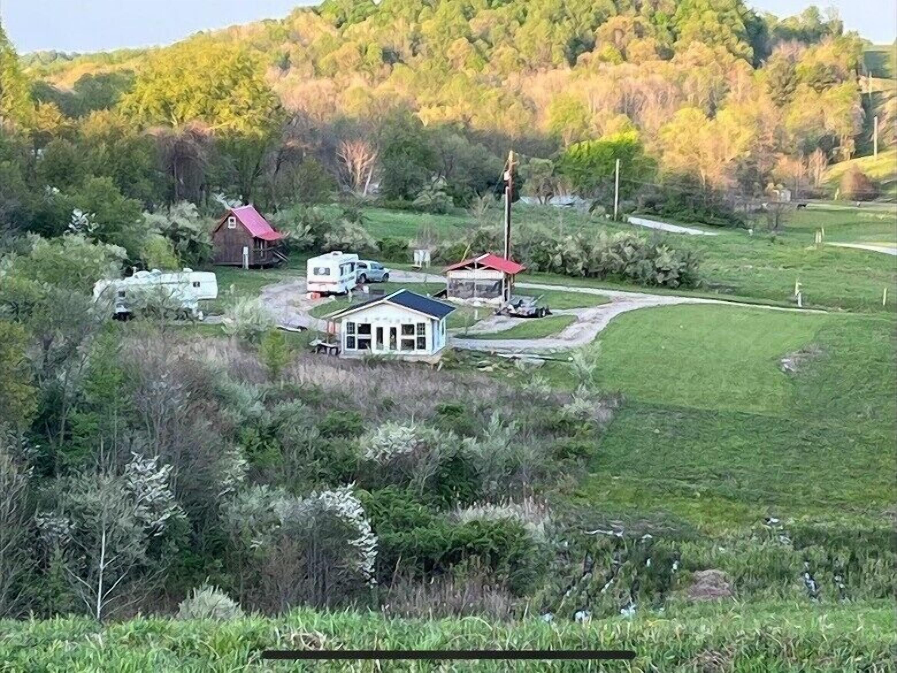 A rural property with a main house, a red-roofed barn, and a white RV.