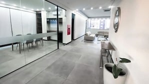Un espace de bureau moderne avec une longue table, des chaises, un canapé et une plante en pot.
