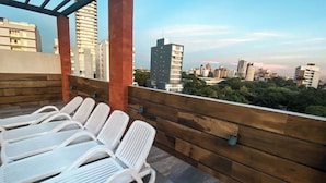 Une terrasse sur le toit, avec des chaises longues blanches et un mur en bois.