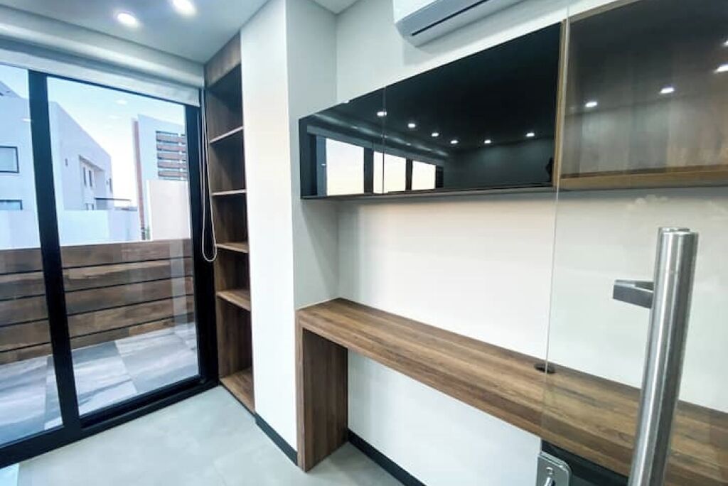 A modern kitchen with built-in cabinets, a stainless steel refrigerator, and a sliding glass door leading to an outdoor area.